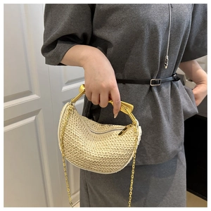 Detail van beige gevlochten tas met moderne goudkleurige metalen handgreep en ketting