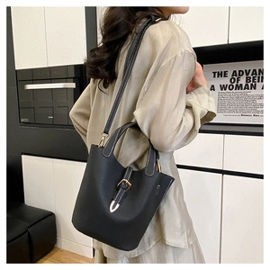 Detail of black lychee grain leather bucket bag with contrast white stitching and strap