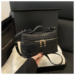 Detailed close-up of woven texture and gold dual zipper on black crossbody box bag