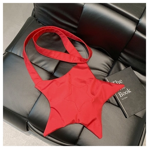 Top view of a red star-shaped padded shoulder bag placed on a black quilted sofa