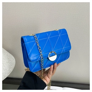 Detail of blue quilted crossbody bag with gold chain strap and magnetic snap closure