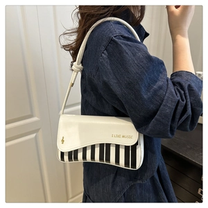 Detail view of piano key crossbody bag with I LIKE MUSIC print and braided strap
