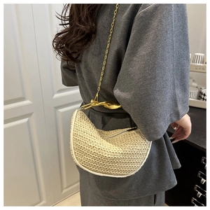Sac hobo en paille avec poignée en métal doré et bandoulière porté par un mannequin