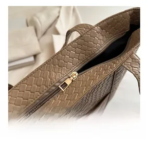 Close-up of the golden zipper closure and intricate woven texture on the brown tote bag
