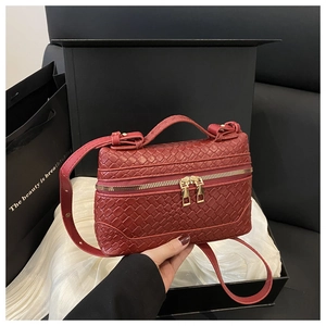 Detailed view of dark red woven leather box bag with gold double zipper and top handle