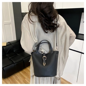 Modern black lychee grain leather bucket bag styled on model in minimalist interior