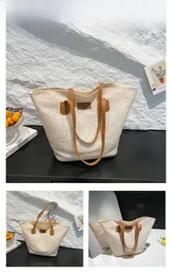 Detailed close-up of beige woven straw tote bag with brown faux leather straps and buckle