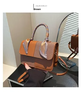 Detailed view of a brown vintage crossbody bag with a silk scarf handle and leather stitching