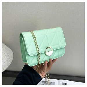 Close-up of mint green quilted PU leather bag with golden chain and round buckle