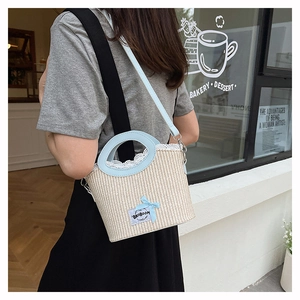 Détail du sac seau en paille avec poignées en cuir bleu clair et bordure en dentelle
