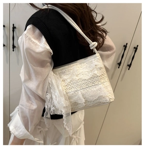 Détail d'un sac à bandoulière en dentelle blanche avec un nœud, porté à l'épaule