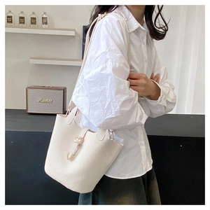 Detail of white lychee grain leather bucket bag with silver buckle and crossbody strap