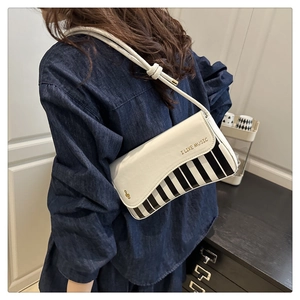 Close-up of retro piano keyboard saddle bag with gold I LIKE MUSIC text on denim outfit