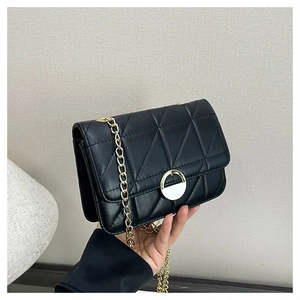 Detail view of black quilted crossbody bag with gold chain strap and metal clasp