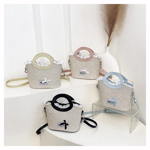 Détail de sacs seaux en paille avec bordure en dentelle blanche et nœuds décoratifs