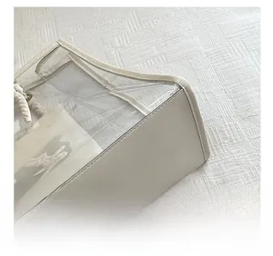Detail of transparent PVC tote bag featuring cream leather trim and cotton rope handle