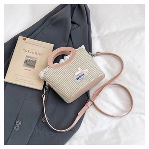 Détail d'un sac en paille tissé à la main avec anse en cuir rose et bordure en dentelle