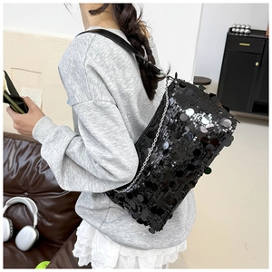 Detail of black sequined shoulder bag with wide leather strap and silver chain accent