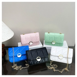 Detail of quilted chain crossbody bags in five colors on a reflective glass surface