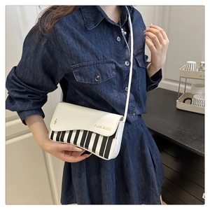 Detail of piano key design on shoulder bag with golden music lettering and treble clef