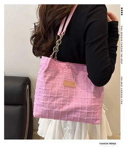 Detailed close-up of pink waffle texture tote bag with metal chain strap and leather patch