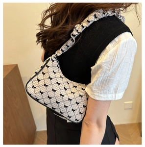 Detail of ruched shoulder strap and vintage black bow patterns on the cream plaid handbag