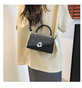 Detail view of black sequined flap bag with silver heart buckle on model's shoulder