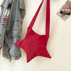 Vibrant red star-shaped canvas crossbody bag with wide strap on a white wall
