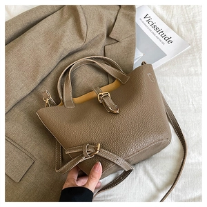 Detail shot of khaki lychee grain leather tote bag with metal buckle and adjustable strap