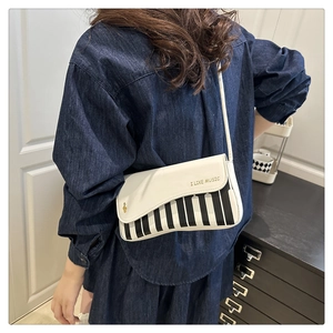 Detailed view of the piano key pattern and golden music notes on the white crossbody bag