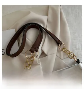Detail of white tote bag featuring textured fabric and leather gold chain shoulder strap