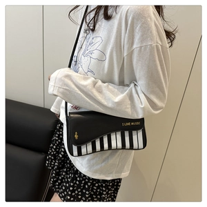 Detail view of piano key pattern and I LIKE MUSIC lettering on the small crossbody bag