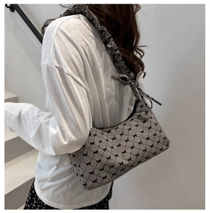 Detail of canvas tote bag featuring black bow patterns and ruffled shoulder strap detail