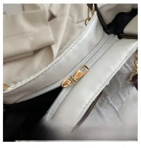 Detail of smooth gold zipper on premium white textured faux leather tote bag