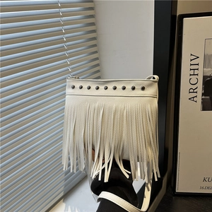 White fringe bucket bag with silver rivets and chain strap shown in a modern interior setting