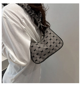 Detail of checkered hobo bag featuring black bow print and ruched shoulder strap