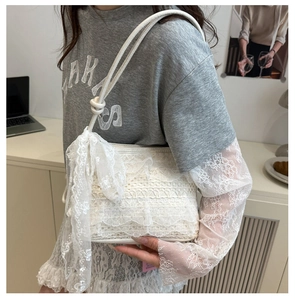 Vue détaillée du sac sous le bras en dentelle blanche avec motifs floraux et nœuds rubans