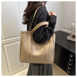 Detail of minimalist beige tote bag showing large capacity and woven texture on model