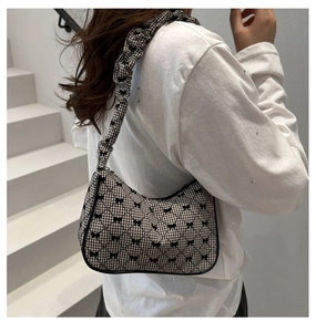 Detail of checkered shoulder bag featuring bow patterns and a pleated strap design