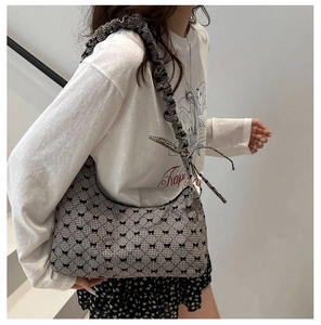 Detail of canvas tote with black and white plaid pattern and bow tie shoulder strap