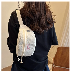 Détail du sac de poitrine en nylon blanc avec broderie ruban rose et étiquette FANYISSA