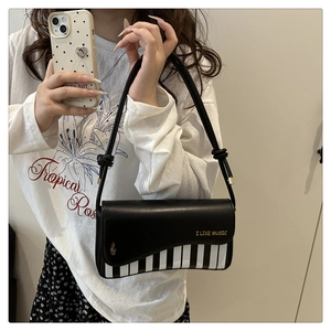 Detail of piano key拼接 and golden musical note embroidery on black leather handbag