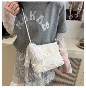 Détail du sac à bandoulière en dentelle blanche avec nœuds et texture de tissu délicat