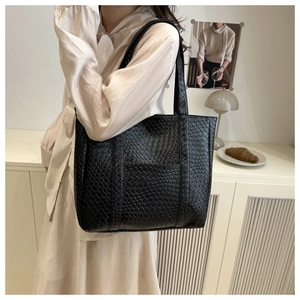 Close-up of black woven leather tote bag with a minimalist square texture on a shoulder strap