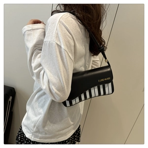 Detail of piano key handbag with I LIKE MUSIC lettering worn as a crossbody shoulder bag