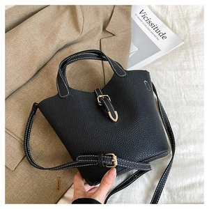 Detail view of black lychee leather bag with white contrast stitching and metal buckle
