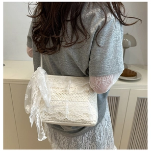 Détail du sac à bandoulière en dentelle blanche avec grand nœud sur le mannequin