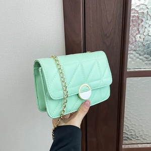 Mint green quilted crossbody bag with gold chain strap and circular metal buckle detail