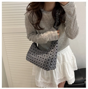 Detail of checkered hobo bag with black bows and ruffled strap on model