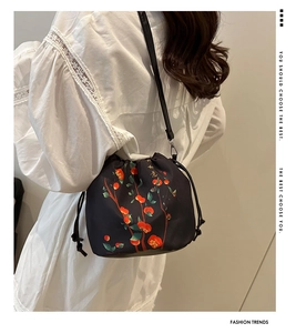 Detail of black drawstring bag with floral embroidery and Ruyi calligraphy on model